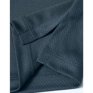 A close-up of a dark grey textured fabric showcasing the details of a sustainable knit polo shirt.