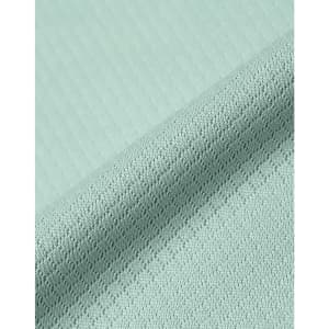 A close-up of a light mint green jacquard knit fabric with a textured pattern. The material appears soft and sustainable.