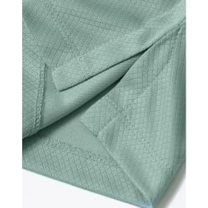 A close-up of a light green sustainable jacquard knit polo shirt featuring textured fabric and stitching details.