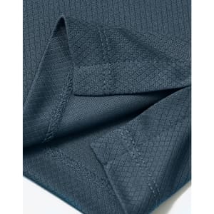 A close-up of a dark teal fabric with a jacquard knit texture and visible stitching details.