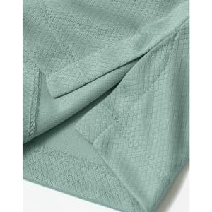 A close-up of a light green sustainable jacquard knit fabric, featuring textured detailing and stitching.