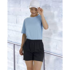 A model wears black bamboo charcoal sports shorts paired with a light blue top and a white cap against a textured background.