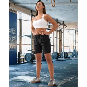 Unisex mercerised cotton shorts in black, displayed on a model in a gym setting. The model wears a white crop top.