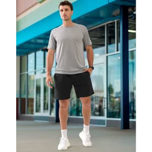 A man is wearing unisex grey mercerised cotton shorts with a matching grey shirt and white sneakers in an outdoor setting.