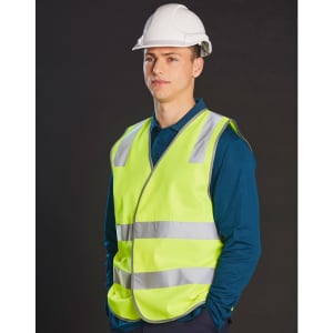 A high visibility safety vest in fluorescent yellow with reflective shoulder tapes, worn over a blue shirt, paired with a white hard hat.