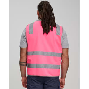 A pink safety vest featuring shoulder reflective tapes and grey stripes, worn by a person from behind.