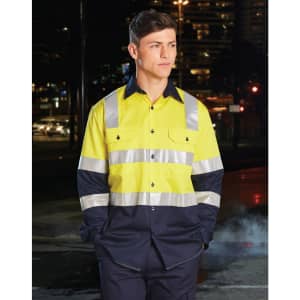 A safety shirt in bright yellow with navy blue sleeves and reflective tape, displayed on a model at night.