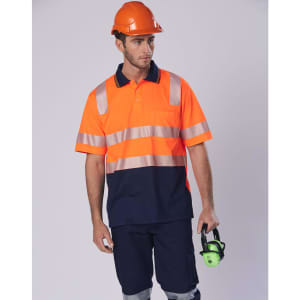 An orange and navy work polo shirt with reflective stripes, worn by a man holding hearing protection, against a neutral background.