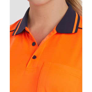 A close-up of an orange polo shirt with navy blue collar detailing and buttons. The shirt features a pocket and has a logo.