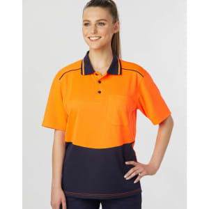 A woman models a bright orange and navy blue unisex polo shirt with a pocket and contrasting details.