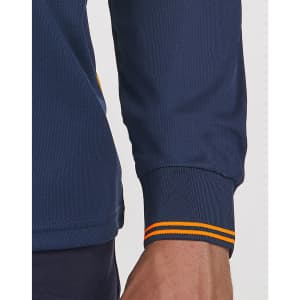 A close-up of a navy blue long-sleeved polo shirt with segmented orange-striped cuffs, featuring a logo.