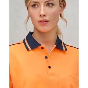 A close-up of a woman wearing a hi-vis orange long-sleeve polo with a navy collar and detailing.