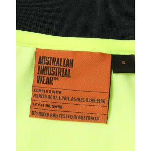 A label from a high-visibility yellow safety polo shirt featuring orange text and a black background.