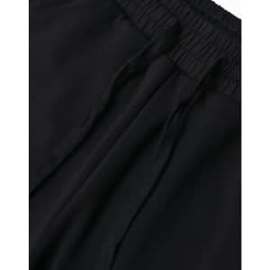 A close-up view of black unisex sweatpants featuring an elastic waistband and drawstrings. The image includes a logo.