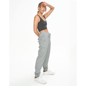 A model wears grey unisex airlayered CVC sweatpants paired with a black crop top and white sneakers.