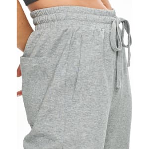 A pair of grey unisex sweatpants with side pockets and an elastic waistband. Features a brand logo.