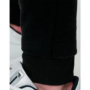 Black poly/cotton terry sweat pants with a fitted cuff, paired with sporty footwear.
