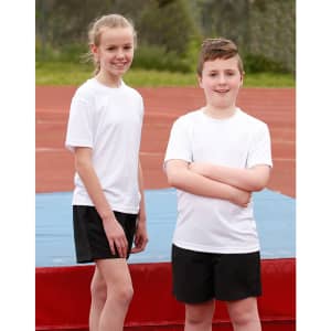 Two children wearing white short sleeve t-shirts and black shorts stand on a sports field. One child has their arms crossed.