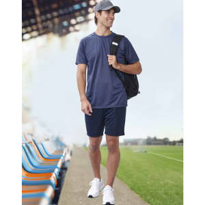 A man wearing a navy blue short-sleeve performance T-shirt and navy shorts, carrying a black backpack.