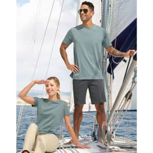 A men's premium cotton short-sleeve tee shirt in light blue, worn by a man on a sailboat, with a woman seated nearby.
