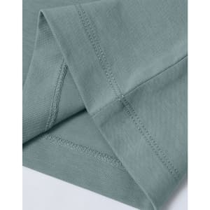 A close-up of a light green premium cotton T-shirt, highlighting the sleeve and stitching details. The shirt has a logo.