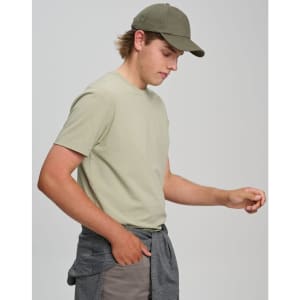 A light olive green men's premium cotton t-shirt worn with a matching cap and casual pants, featuring a logo.