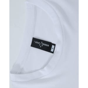 A white long-sleeve tee with a round neckline, featuring a label and a logo.