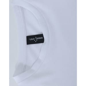 A white long sleeve tee shirt with a rounded neckline and a tag displaying branding.
