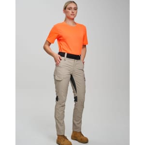 A pair of beige rip-stop poly/cotton stretch work pants displayed on a model wearing an orange shirt and sturdy boots.