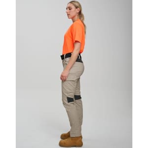 Work pants in light khaki with black accents, paired with an orange shirt. The model stands in profile.