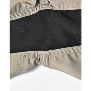 A close-up of beige work shorts featuring a black inner lining and stitched seams, with a logo visible.