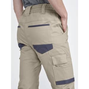 Cuffed unisex work pants in khaki, featuring multiple pockets and a waistband with elastic. Includes branding.
