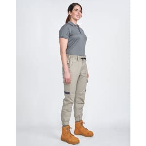 Unisex cotton stretch drill cuffed work pants in khaki, paired with a grey polo and tan work boots. Features pockets and an elastic waistband.