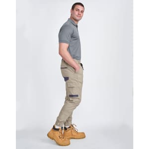 Unisex cotton stretch drill cuffed work pants in khaki with side pockets, paired with a grey polo and yellow work boots.