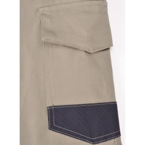 A close-up of unisex cotton stretch drill cuffed work pants in light khaki with a dark navy pocket detailing.