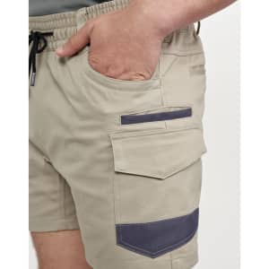 Work shorts in beige with dark navy accents, featuring pockets and an elastic waistband. The shorts have a logo.