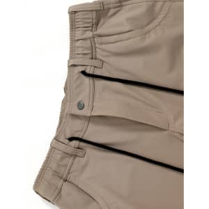 Beige water-repellent flexi work pants featuring elastic waistband and zippered pockets, with branding on the fabric.