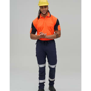 A man wearing a high-visibility orange polo shirt and navy work pants with reflective tape, along with a yellow hard hat.