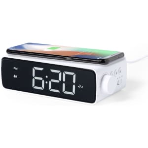 A white multifunction alarm clock with a digital display and a wireless charging pad on top for smartphones.