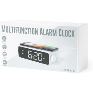 A multifunction alarm clock in a white box, featuring a digital display and a wireless charging section for phones.