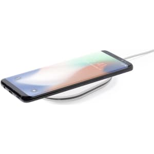 A wireless charger in white with a smartphone placed on top, showcasing a sleek design and modern aesthetics.