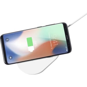 A wireless charger in white with a smartphone placed on top, displaying a battery charging icon.