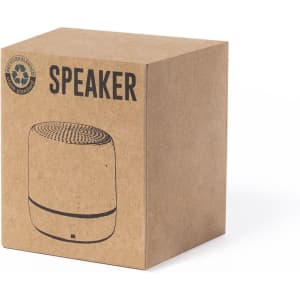 A brown cardboard box containing a cylindrical speaker. The speaker has a textured top and features a logo.