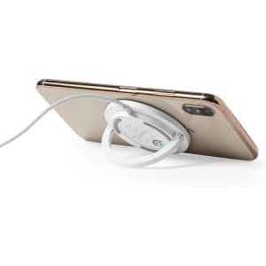 A wireless charger in white, placed behind a smartphone, with a charging cable attached.