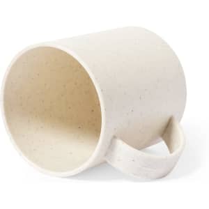 A cream-coloured coffee mug with a textured finish and a handle, featuring a simple design and a logo.