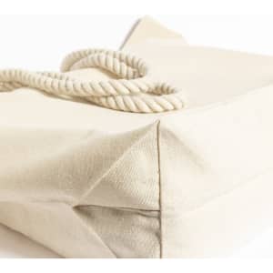 A cream tote bag with a textured surface and a twisted rope handle, featuring a simple, minimalist design.