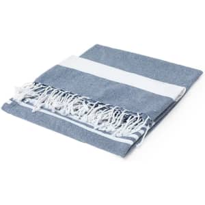 A blue and white striped beach mat with tassels, neatly folded. It features a soft texture and a simple design.