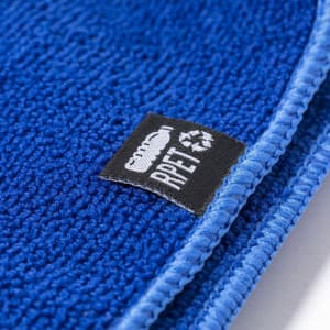 A blue absorbent towel with a textured surface and a small logo tag attached.