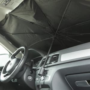 A black sunshade rests inside a car, extending from the dashboard to block sunlight. It has a central support and a handle.