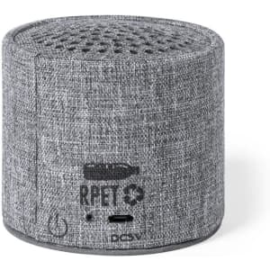 A grey speaker with a textured fabric finish and a logo at the base, designed for portable sound.